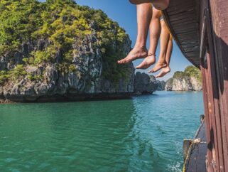 People diving into turquoise water from boat in tropical landscape. {{brizy_dc_image_alt imageSrc=